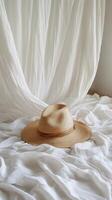 A hat sits on top of a bed with white sheets photo
