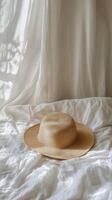 A hat sits on a bed with white sheets photo