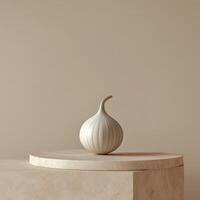 A white onion sits on a pedestal in front of a beige wall photo