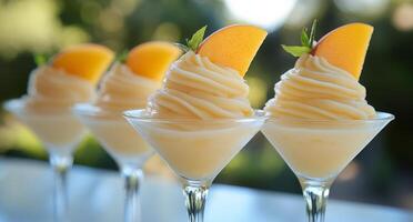 Three dessert glasses with peach slices on top photo