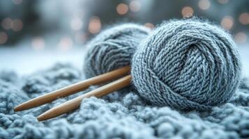 Two knitting needles and a ball of yarn on a snowy background photo