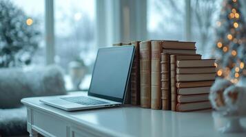 A laptop and books on a desk in front of a window photo