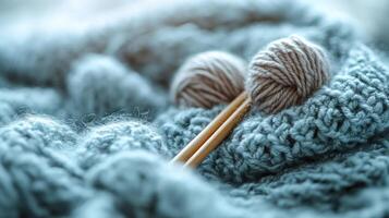 Two knitting needles on a blue knitted blanket photo