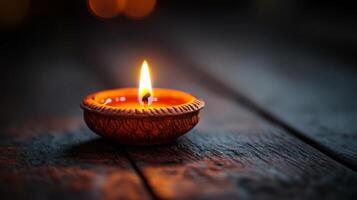A lit candle on a wooden table with blurred background photo