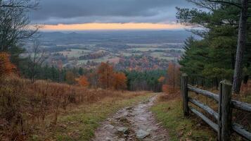 A dirt path leads to a wooden fence on a hillside photo