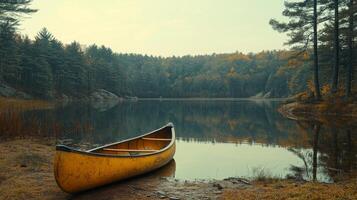 A yellow canoe sits on the shore of a lake photo
