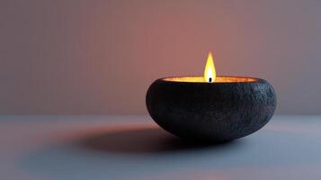 A black candle is lit in a small black bowl photo