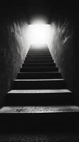 Black and white photo of stairs leading to a light