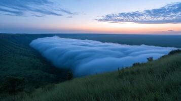 A view of the clouds rolling over the edge of a cliff photo