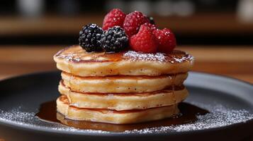 A stack of pancakes with berries and syrup on top photo