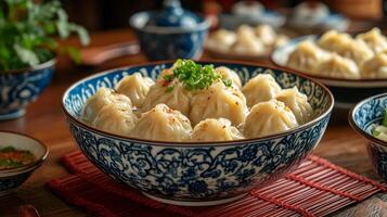 A bowl of dumplings with chopsticks and a bowl of soup photo