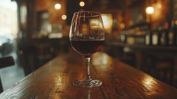 A glass of red wine sitting on a wooden table photo