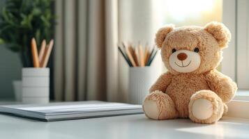 A teddy bear sits on a desk near a window photo