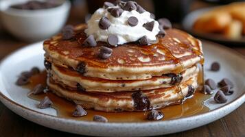 A stack of pancakes topped with whipped cream and chocolate chips photo