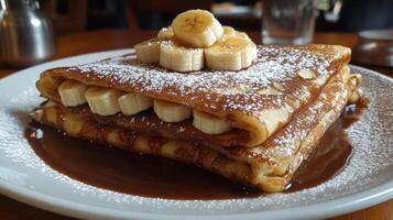 A stack of pancakes with bananas and chocolate syrup photo