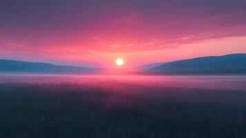 A sunset over a field with grass and mountains photo