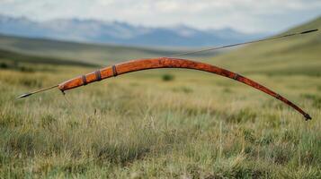 Old wooden bow resting in a field during golden hour with sun setting in the background photo