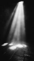 A black and white photo of a light shining through a door