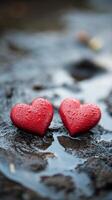 Two red hearts sitting in water on a rock photo