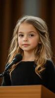 A little girl is standing at a podium with a microphone photo