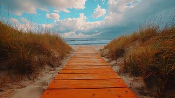 A wooden path leads to the beach with grass and clouds photo