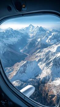 A view out of an airplane window of snow covered mountains photo