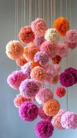 A large group of pink and orange pom poms hanging from strings photo