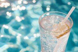 A glass of water with lemon and ice in front of a pool photo