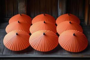 A group of eight orange umbrellas sitting on a wooden table photo