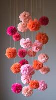Pink and orange tissue paper flowers hanging from strings photo