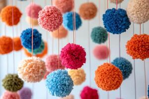 A large group of colorful pom poms hanging from strings photo
