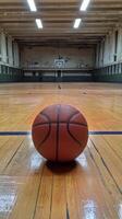 Basketball ball on the floor of an empty gym photo