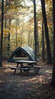 Peaceful camping setup in a serene forest with a tent and picnic table in autumn photo