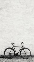 A black and white photo of a bicycle against a white wall