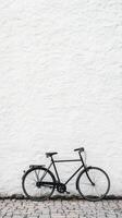 A black bicycle is leaning against a white wall photo