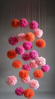 Pink and orange pom poms hanging from strings photo