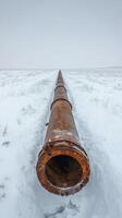 A rusted pipe in the middle of a snowy field photo