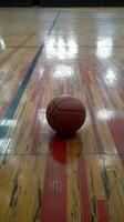 A basketball on the floor of an indoor basketball court photo