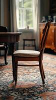Classic wooden chair positioned beside a dark wooden table in an elegant room setting photo