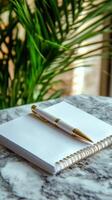 A white notepad with a gold pen on top of a marble table photo