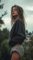 A woman in a sweatshirt and shorts standing in front of trees photo