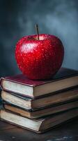 An apple sits on top of a stack of books photo