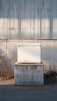 A white box sitting on a concrete block in front of a building photo