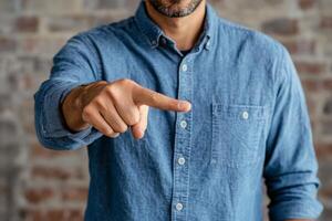 A man in a blue shirt pointing at something photo