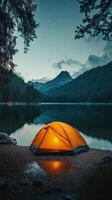 Camping tent on the shore of a lake at night photo