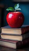 A red apple sitting on top of three books photo