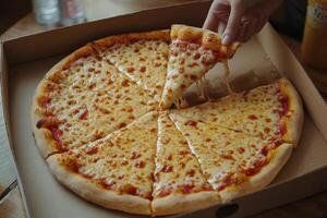 A person is taking a slice of pizza out of a box photo