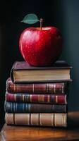 An apple sits on top of a stack of books photo