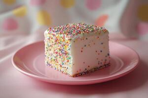 A white cake with sprinkles on a pink plate photo
