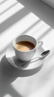 A cup of coffee on a white table with sunlight photo